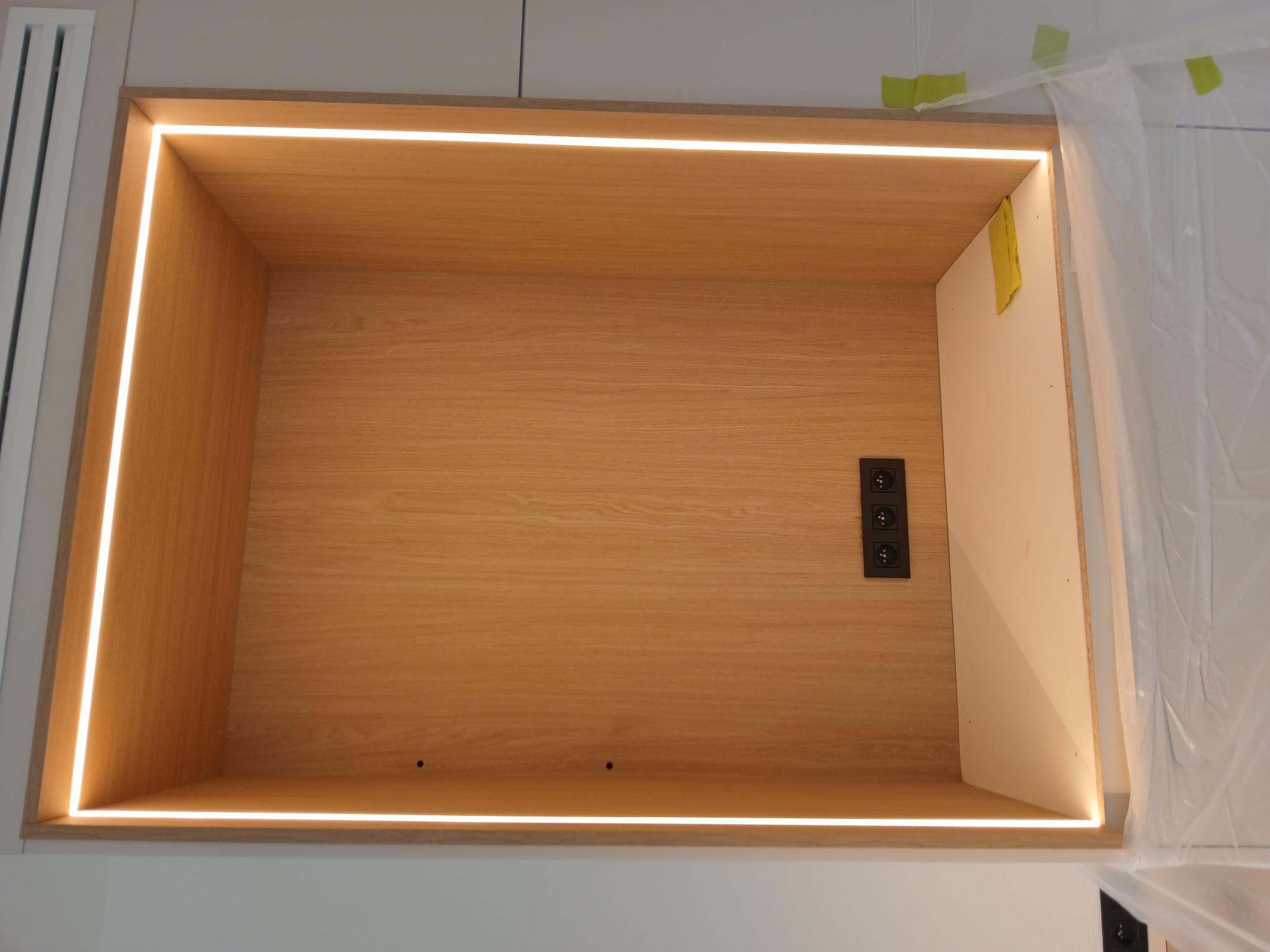 Ingebouwde houten nis met een omlopende ledstrip en drie zwarte stopcontacten