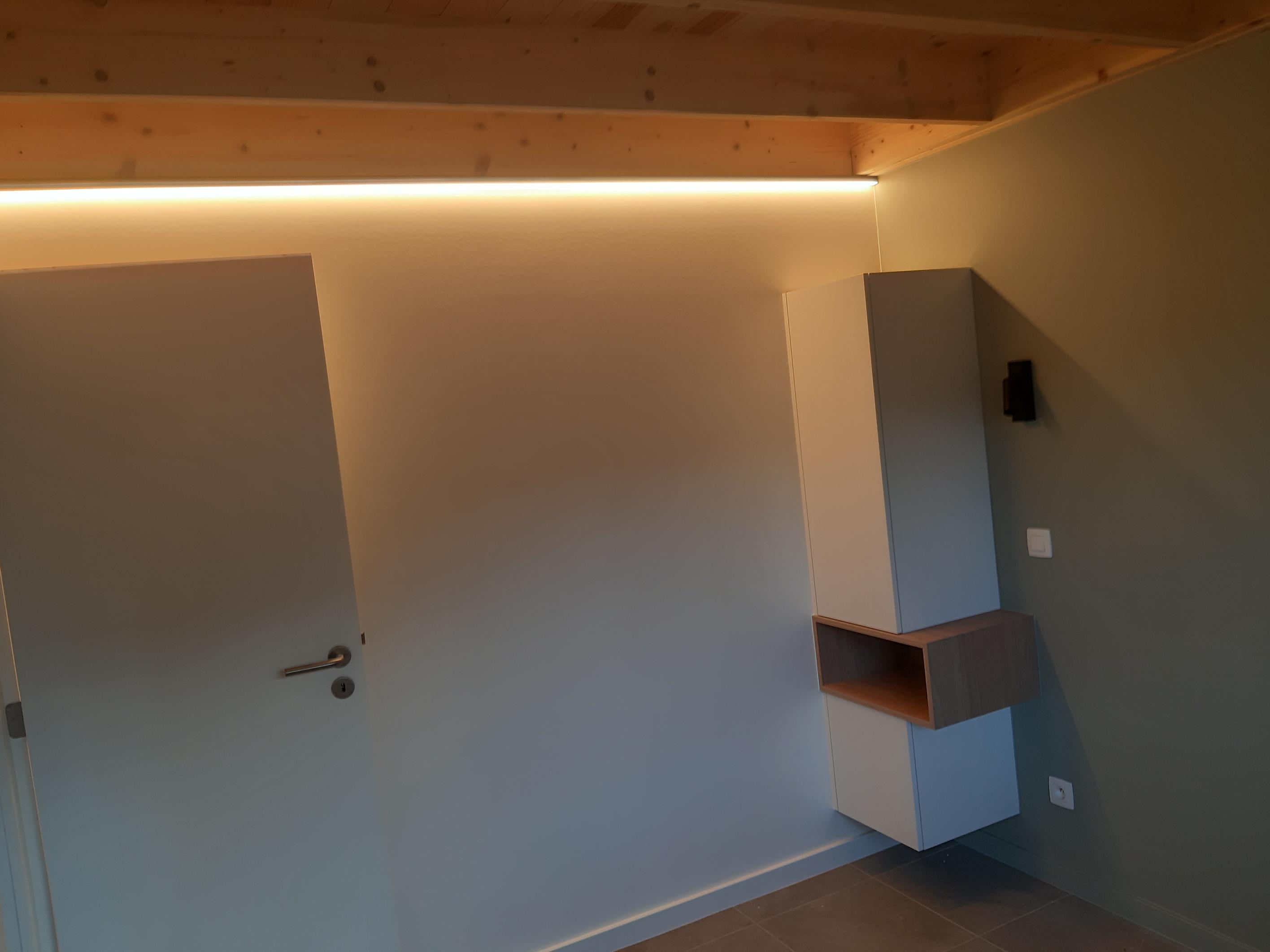 Warme ledstrip die langs de houten plafondbalk van een slaapkamer loopt