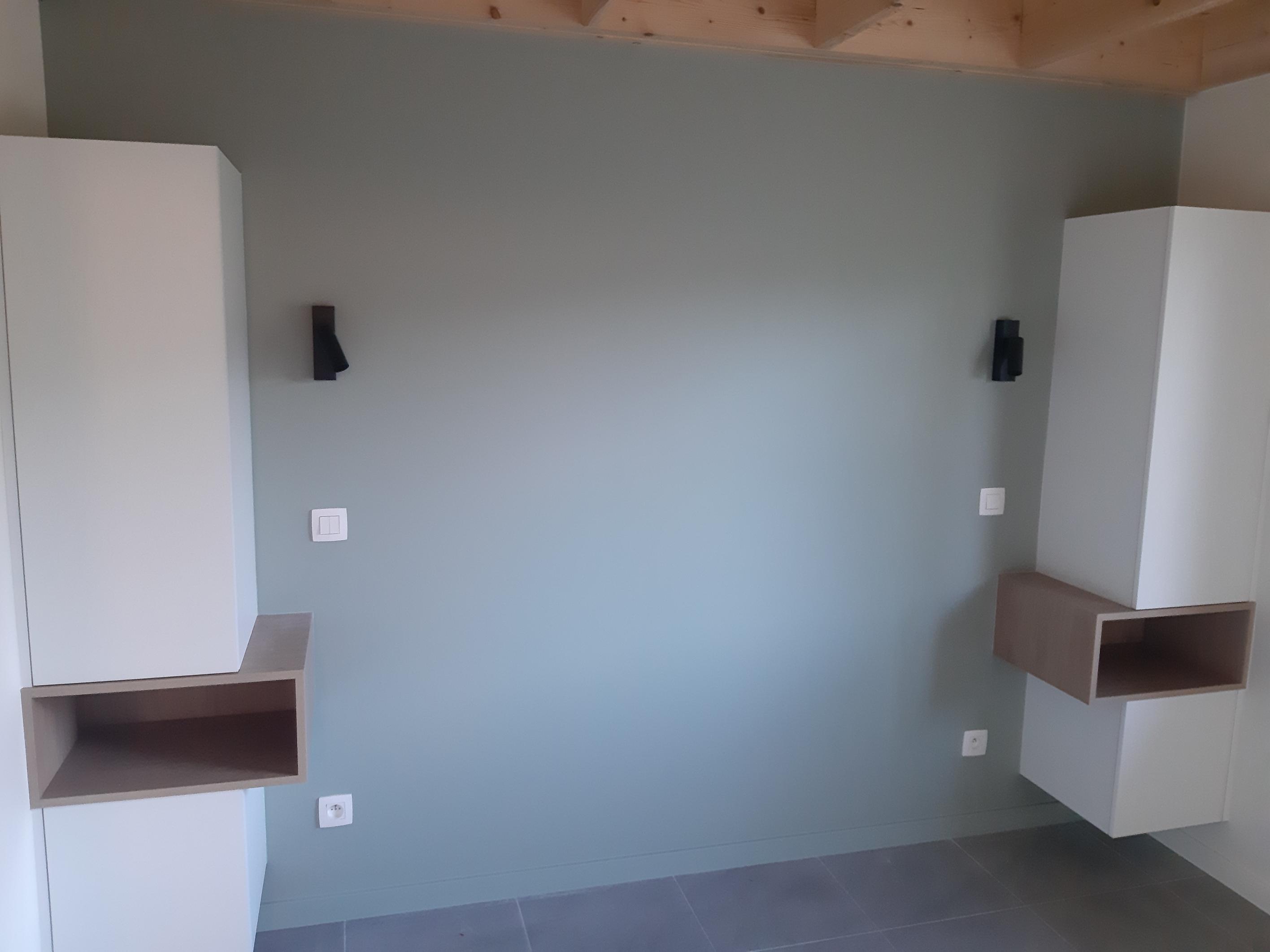 Zwarte leeslampen en schakelaars naast zwevende kasten in een slaapkamer met houten plafond